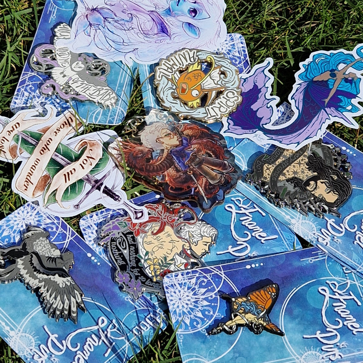 a collection of fantasy inpired items including enamel pins, stickers and keyrings